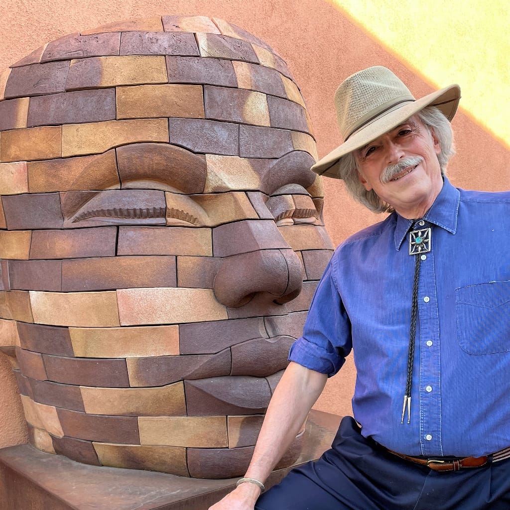 John Pen La Farge standing near a large sculpture of a head